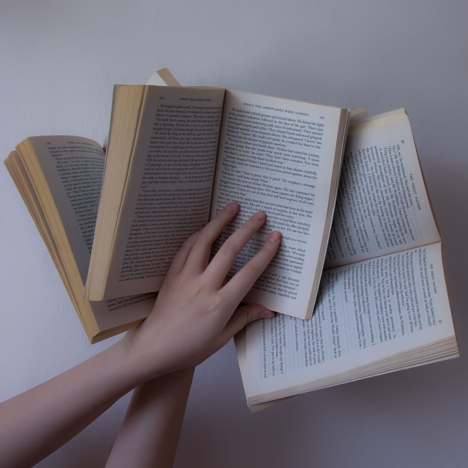 A person effortlessly holding and fanning multiple open book pages.
